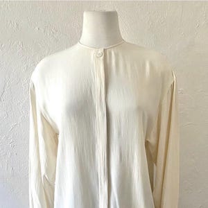 May include: A white long-sleeved button-up shirt with a mandarin collar.