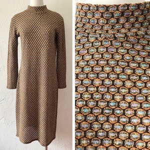 May include: A brown and gold patterned dress with a mock neck and long sleeves. The dress has a geometric pattern with a subtle shimmer.