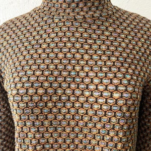 May include: A black mock neck sweater with a geometric pattern in shades of brown, blue, and gold.