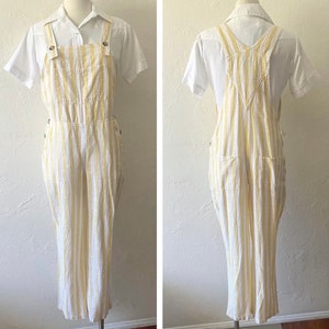 May include: White and yellow striped overalls with a white button-up shirt. The overalls have a wide leg and a relaxed fit.