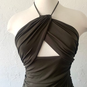 Puede incluir: Un top verde oscuro de tirantes con un detalle de corte en la parte delantera. El top est&aacute; hecho de una tela el&aacute;stica y sedosa y tiene un detalle anudado en el escote.