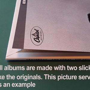May include: Close-up of the spine of a vinyl record album. The album cover is white with a black and white photo of a person. The album is titled "Yesterday and Today" by The Beatles. The Capitol Records logo is visible on the spine.