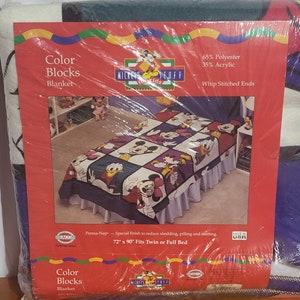 Puede incluir: Una manta "Color Blocks" empaquetada con un dise&ntilde;o de retazos con personajes de Mickey Mouse. La manta es roja, morada, blanca y azul. El embalaje indica que la manta mide 183 cm x 229 cm y se adapta a una cama individual o de matrimonio.