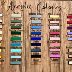 May include: Wooden color chart labeled "Acrylic Colours" with color swatches in various shades like white, blue, green, and pink. Each color is labeled with its name, such as "Sky Blue" and "Cherry Red".
