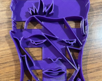 May include: Purple plastic cookie cutter shaped like a person's face with a lightning bolt design.