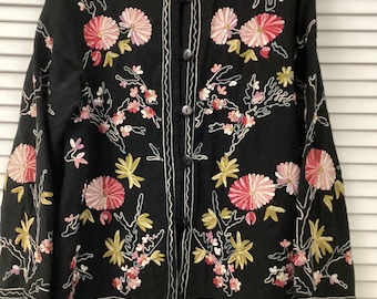 May include: Black jacket with floral embroidery in pink, white, and yellow. The jacket features a round collar, button closure, and white trim. The floral design is embroidered across the front and sleeves.