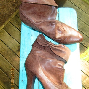 May include: Two pairs of brown leather ankle boots. One pair is flat and the other pair has a high heel.