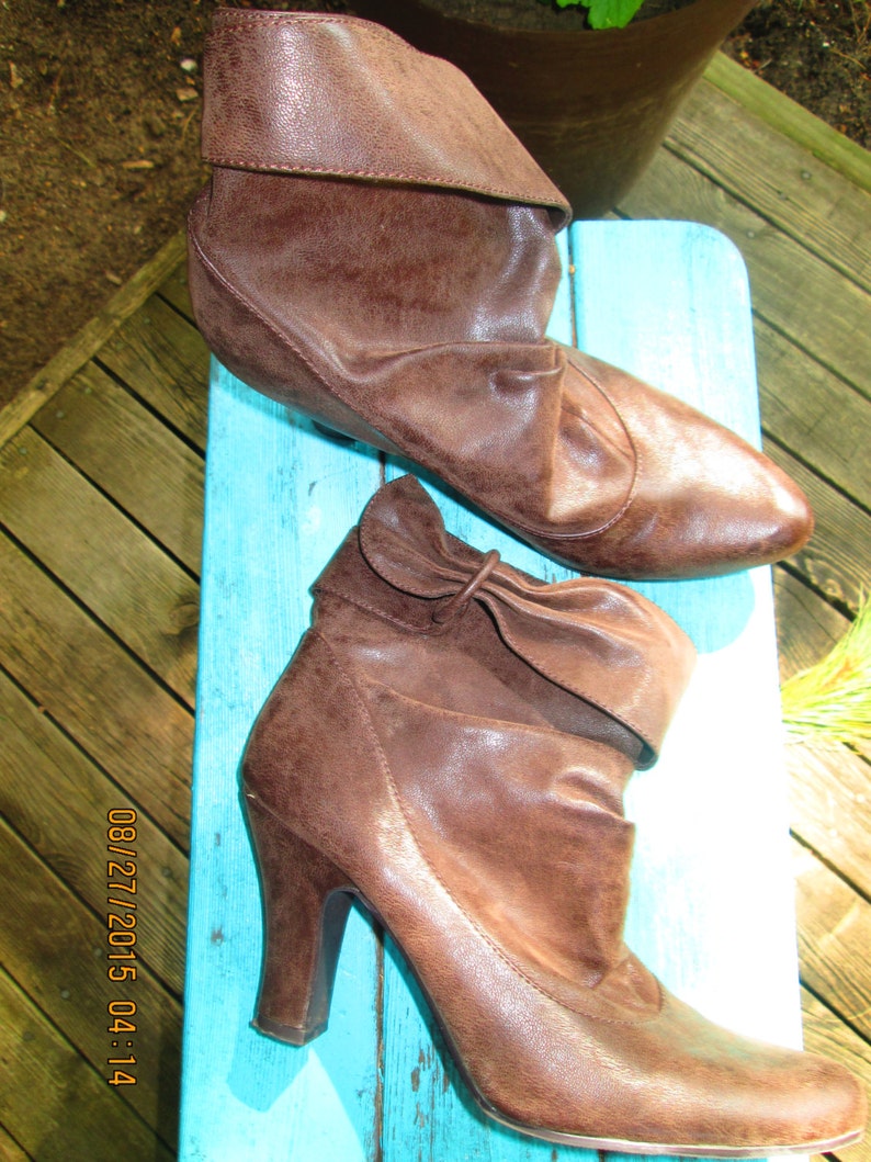 May include: Two pairs of brown leather ankle boots. One pair is flat and the other pair has a high heel.