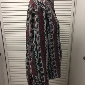 May include: A long-sleeved button-down shirt with a geometric pattern in shades of red, green, blue, and gray.