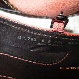 May include: Close-up of the inside of a brown leather sandal with a pink strap. The sandal has the following text printed on the insole: D15793 6 B C04 202890 MADE IN BRAZIL 06/06/2015 08:26