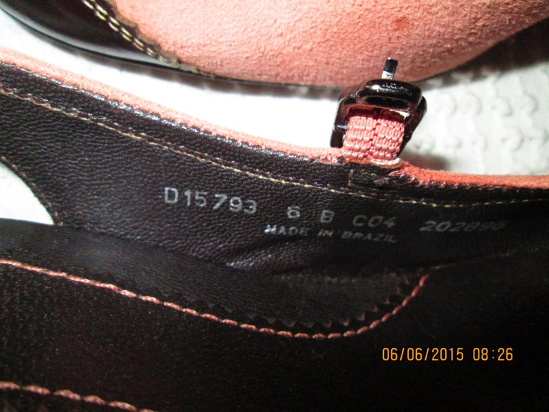 May include: Close-up of the inside of a brown leather sandal with a pink strap. The sandal has the following text printed on the insole: D15793 6 B C04 202890 MADE IN BRAZIL 06/06/2015 08:26