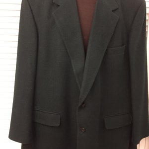 Peut inclure: Un blazer vert foncé avec une fermeture à deux boutons et deux poches sur le devant.