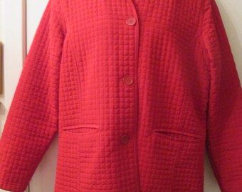 May include: A red quilted jacket with a button fastening and two pockets. The jacket has a small collar and long sleeves.