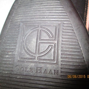 May include: Close-up of a brown leather shoe sole with the Cole Haan logo and a date stamp of 06/06/2015 08:26.