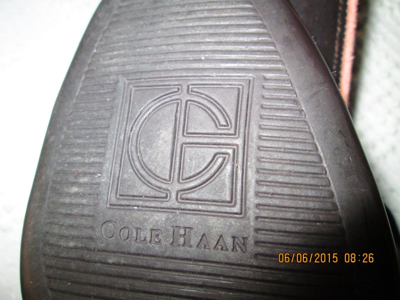 May include: Close-up of a brown leather shoe sole with the Cole Haan logo and a date stamp of 06/06/2015 08:26.