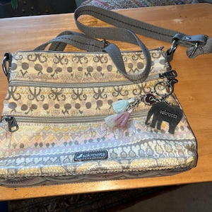 May include: A white ceramic mug with a black handle and the text "But First, Coffee" in a black, handwritten-style font. The mug is on a white surface.