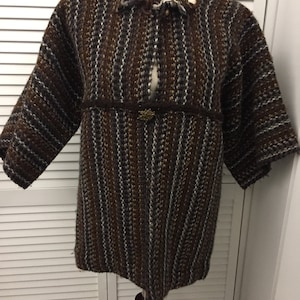 May include: A brown, black, and white striped knitted jacket with a frayed neckline and a decorative button.