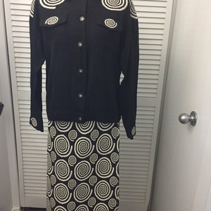 May include: A black button-up shirt with white spiral designs on the shoulders and a matching black and white spiral skirt.