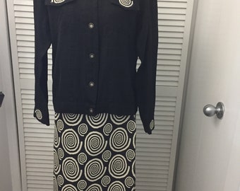 May include: A black button-up shirt with white spiral designs on the shoulders and a matching black and white spiral skirt.
