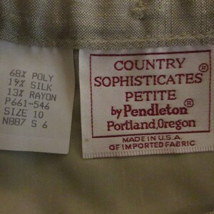 May include: A beige garment label featuring the text Country Sophisticates Petite by Pendleton Portland, Oregon, Made in U.S.A. of imported fabric. A secondary white label lists 68% poly, 19% silk, 13% rayon, size 10, and code P661-546 N887 S 6.