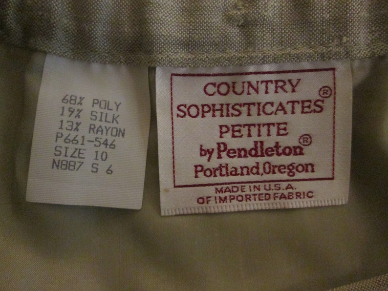 May include: A beige garment label featuring the text Country Sophisticates Petite by Pendleton Portland, Oregon, Made in U.S.A. of imported fabric. A secondary white label lists 68% poly, 19% silk, 13% rayon, size 10, and code P661-546 N887 S 6.