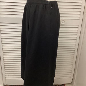 May include: A black skirt with a zipper and button closure. The skirt is made of a thick, woven fabric.