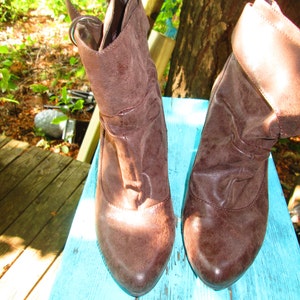 May include: A pair of brown leather ankle boots with a fold-over design. The boots have a pointed toe and a low heel.