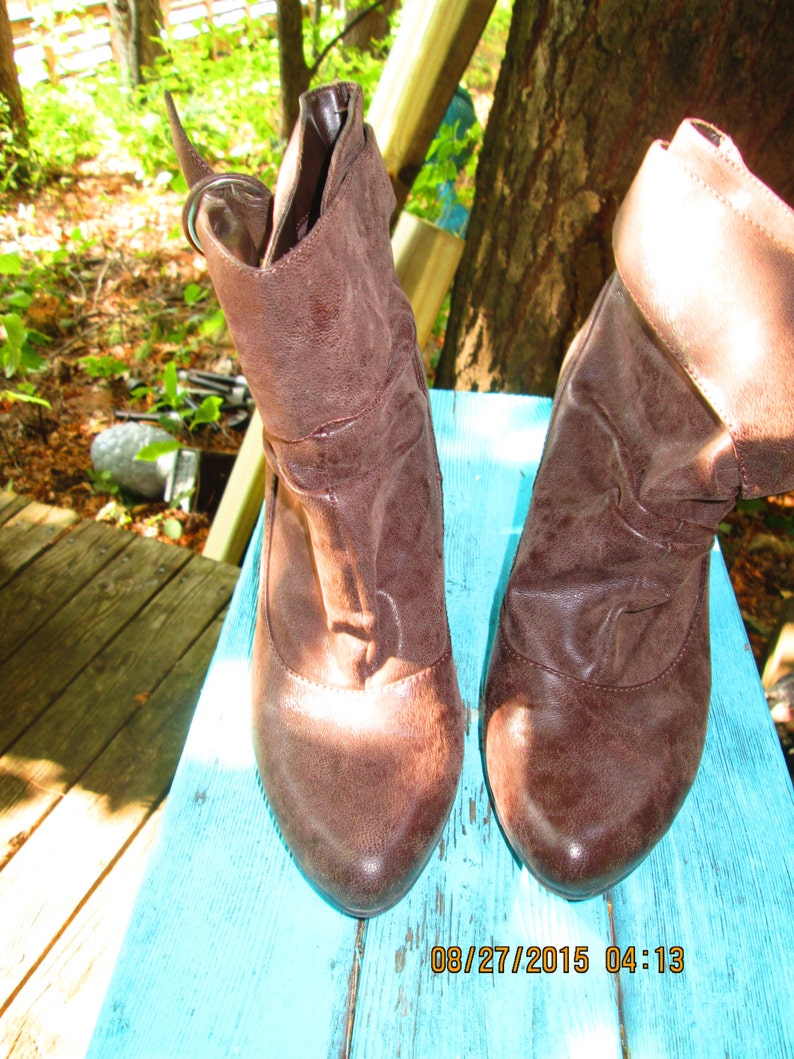 May include: A pair of brown leather ankle boots with a fold-over design. The boots have a pointed toe and a low heel.