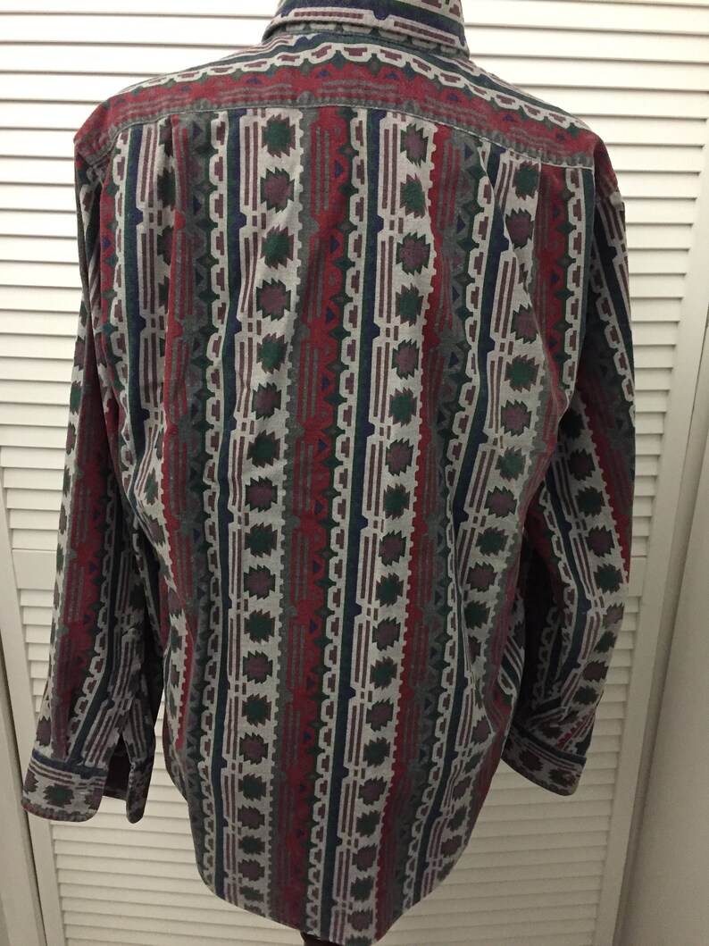 May include: A long-sleeved button-down shirt with a geometric pattern in shades of red, green, blue, and gray.