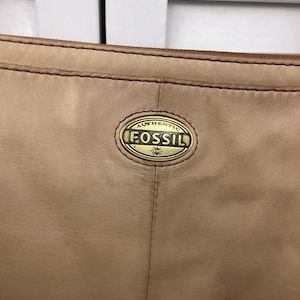 Fossil light tan and brown leather crossbody long shoulder purse Top zipper w 2 back zippered pockets  Fossil medallion on front Very clean