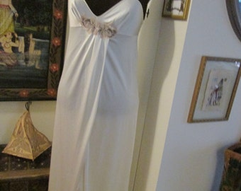 Könnte beinhalten: Ein weißes, seidenes, langes Schlupfkleid mit einem zarten Blumendesign am Oberteil. Das Kleid hat dünne Träger und eine fließende Silhouette.