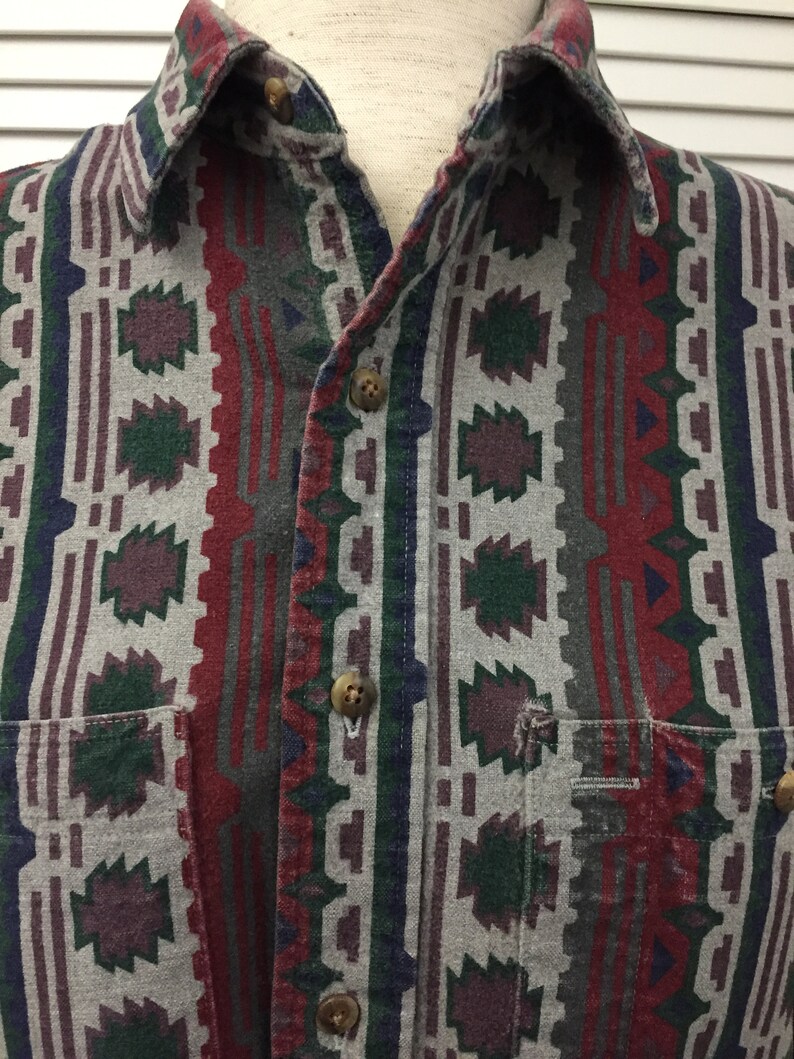 May include: A long-sleeved button-down shirt with a geometric pattern in shades of red, green, blue, and gray.