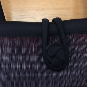 May include: A black woven bag with a black fabric handle. The handle has a knotted detail.