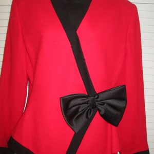 May include: A red blazer with black trim and a large black bow at the waist.