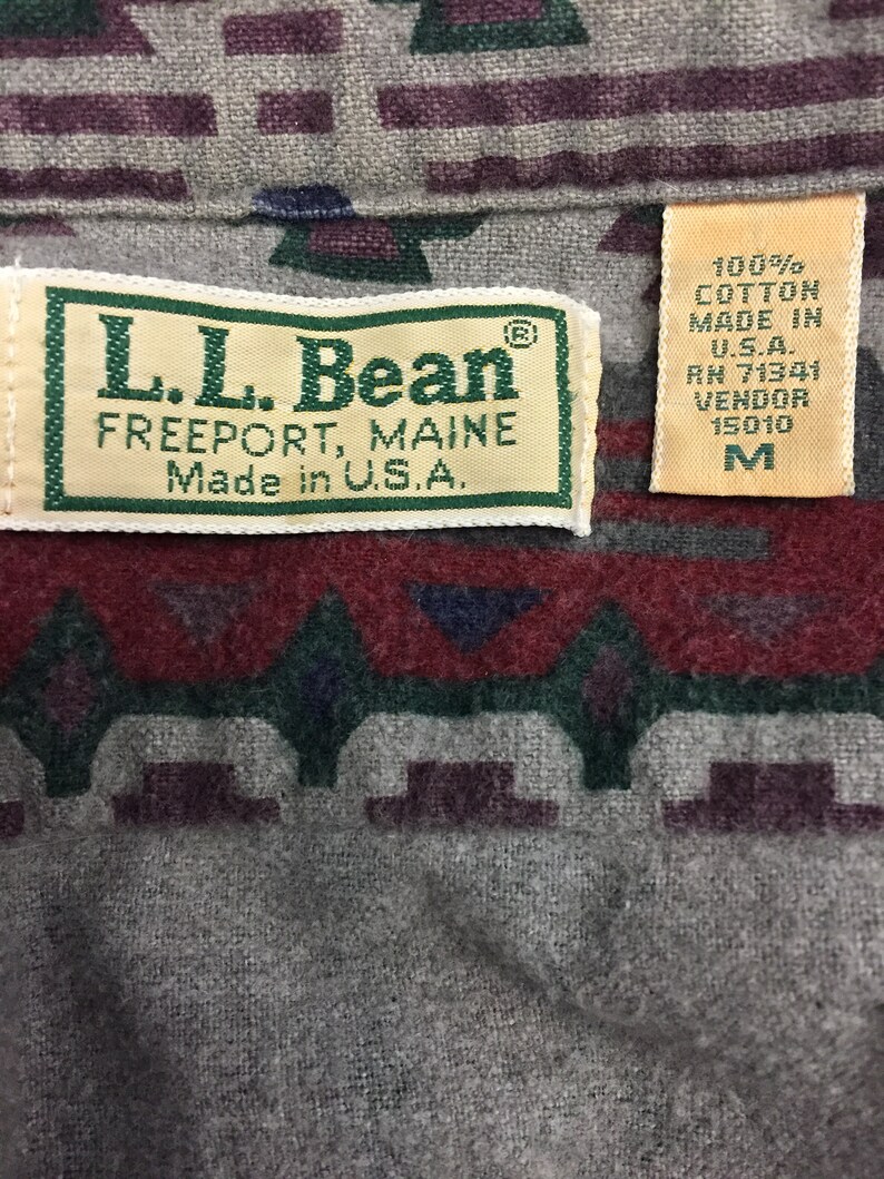 May include: A brown, green, and red patterned flannel shirt with a L.L. Bean label. The label says "L.L. Bean, Freeport, Maine, Made in U.S.A." and has a size tag that says "M".