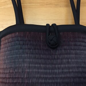 May include: A black woven handbag with a black fabric handle and a knotted closure.
