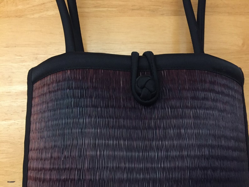 May include: A black woven handbag with a black fabric handle and a knotted closure.