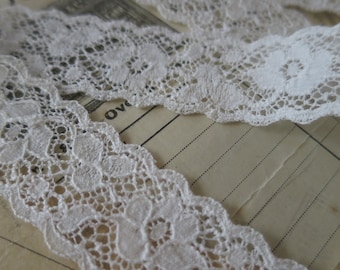May include: White lace trim with a delicate floral pattern. The lace is soft and has a scalloped edge.