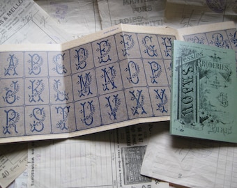 Könnte beinhalten: Ein Vintage-Stickmusterheft mit einem blauen und weißen Alphabet-Design. Das Heft trägt den Titel "Dessins de Broderies" und enthält die Texte "SAJOU" und "Paris".