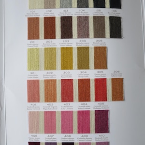 May include: A color chart of embroidery floss with numbered swatches. The colors range from white to black, with shades of brown, orange, red, pink, and purple. The chart is labeled with the color names and numbers.
