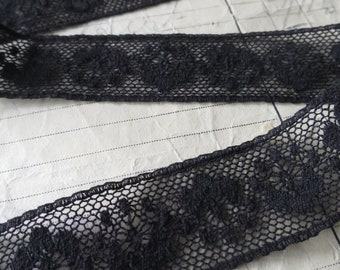Puede incluir: Borde de encaje negro con un delicado diseño floral. El borde está hecho de una tela de malla fina y tiene un borde ligeramente festoneado.