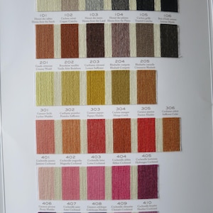 May include: A color chart with 6 rows of 6 small yarn samples, each labeled with a number and a name. The colors range from white to dark brown, with shades of yellow, orange, red, pink, and purple.