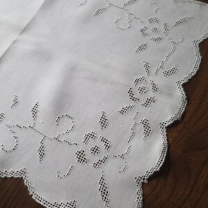 Puede incluir: Camino de mesa de lino blanco con borde festoneado y delicado diseño floral bordado.