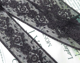 Puede incluir: Borde de encaje negro con un patrón floral. El encaje es delicado e intrincado, con un fondo de malla fina.