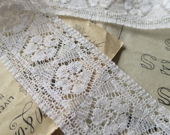May include: White lace trim with a delicate floral pattern. The lace is shown on a piece of paper with handwritten text.
