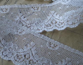 May include: White lace trim with a delicate floral pattern. The lace is soft and has a scalloped edge.