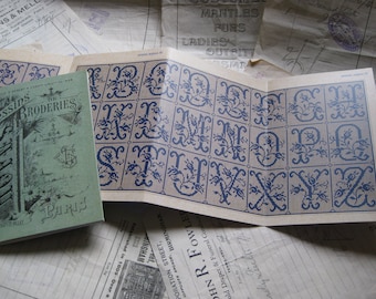 May include: A vintage booklet with a blue and white alphabet design. The booklet is titled "Dessins de Broderies" and has the number 654 printed on the cover. The booklet is open to reveal a page with a blue and white alphabet design.