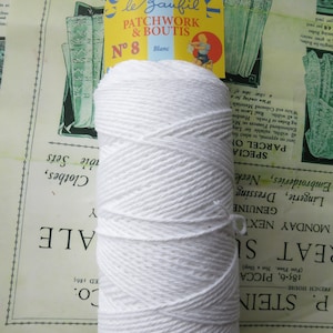 Pode incluir: Uma bola de fio de algodão branco com a etiqueta "le Baufil Cotton Special Patchwork & Boutis N° 8 Blanc".