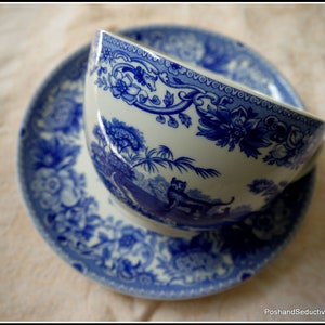 Könnte beinhalten: Ein blaues und weißes Porzellan-Teetassen- und Untertassen-Set mit einem Blumenmuster und einer Darstellung einer Katze. Die Untertasse hat einen gewellten Rand.