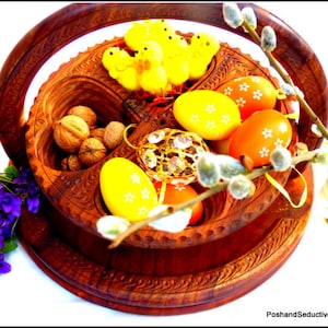 May include: A wooden serving tray with four compartments, featuring a decorative design. The tray is filled with walnuts, yellow and orange Easter eggs, and yellow chicks. A sprig of pussy willow branches with fuzzy buds is placed on top of the tray.